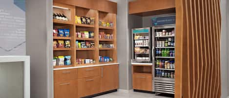 Een snackbar met rekken vol diverse snacks en een koelgedeelte met drankjes.