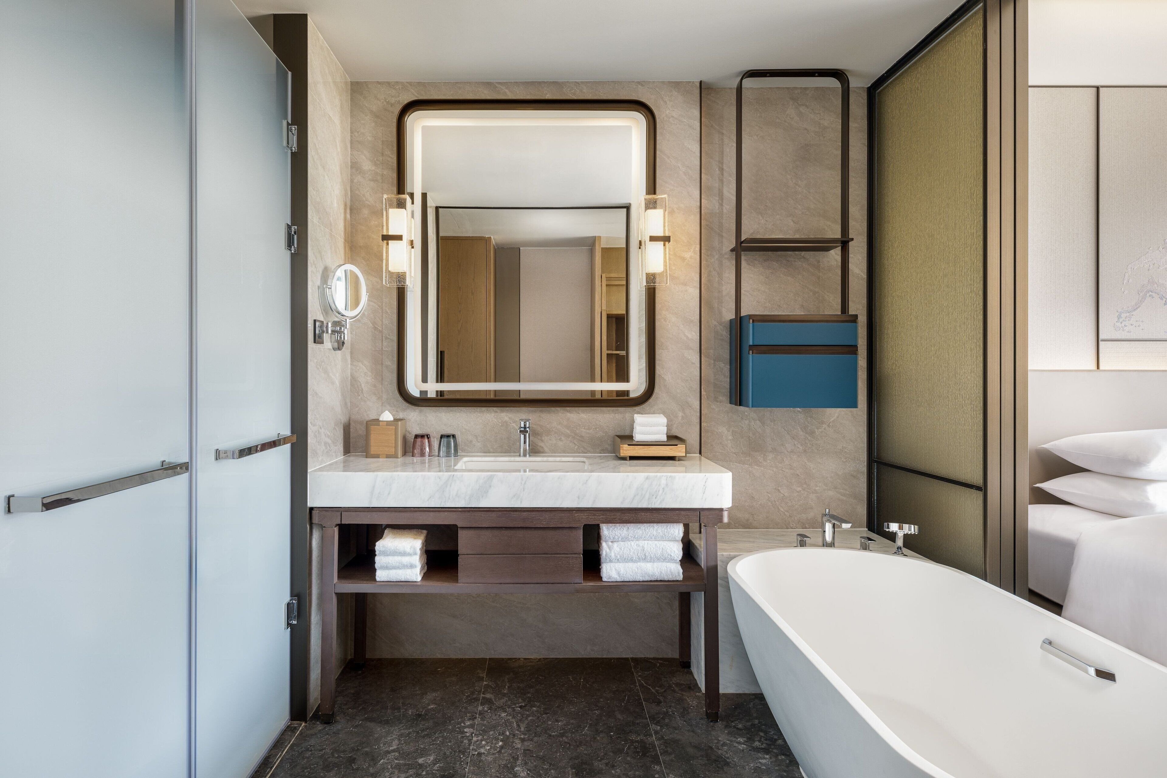 Un baño moderno con un espejo grande, una bañera y un tocador con lavabo.