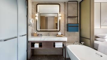 Un baño moderno con un espejo grande, una bañera y un tocador con lavabo.