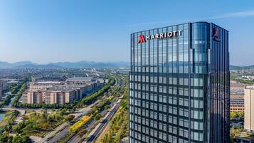 Ein modernes Marriott Hotel mit Glasfassade, umgeben von einer gepflegten Stadtlandschaft und fernen Bergen.
