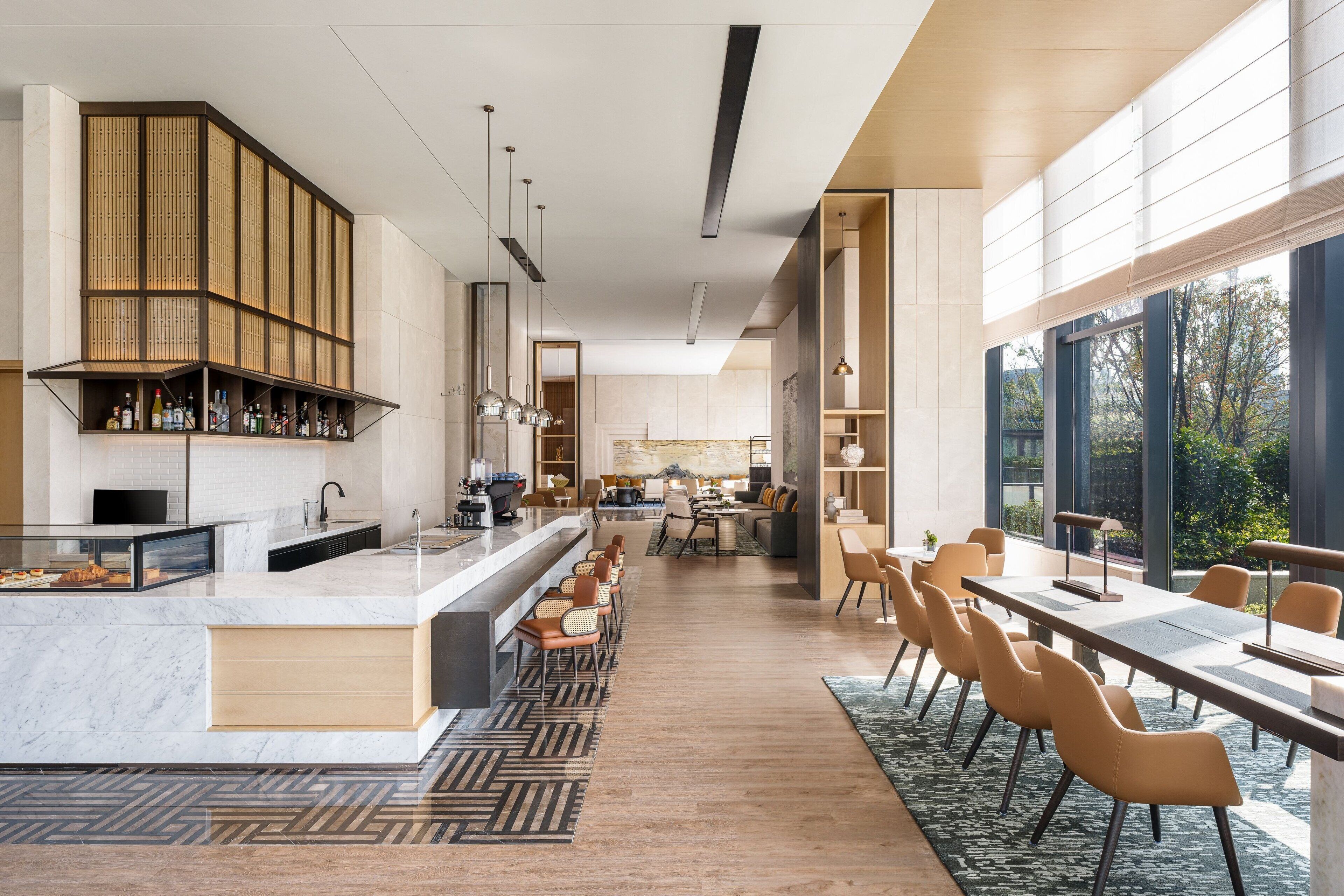 Un moderno vestíbulo de hotel con zona de bar, asientos y vistas al exterior.