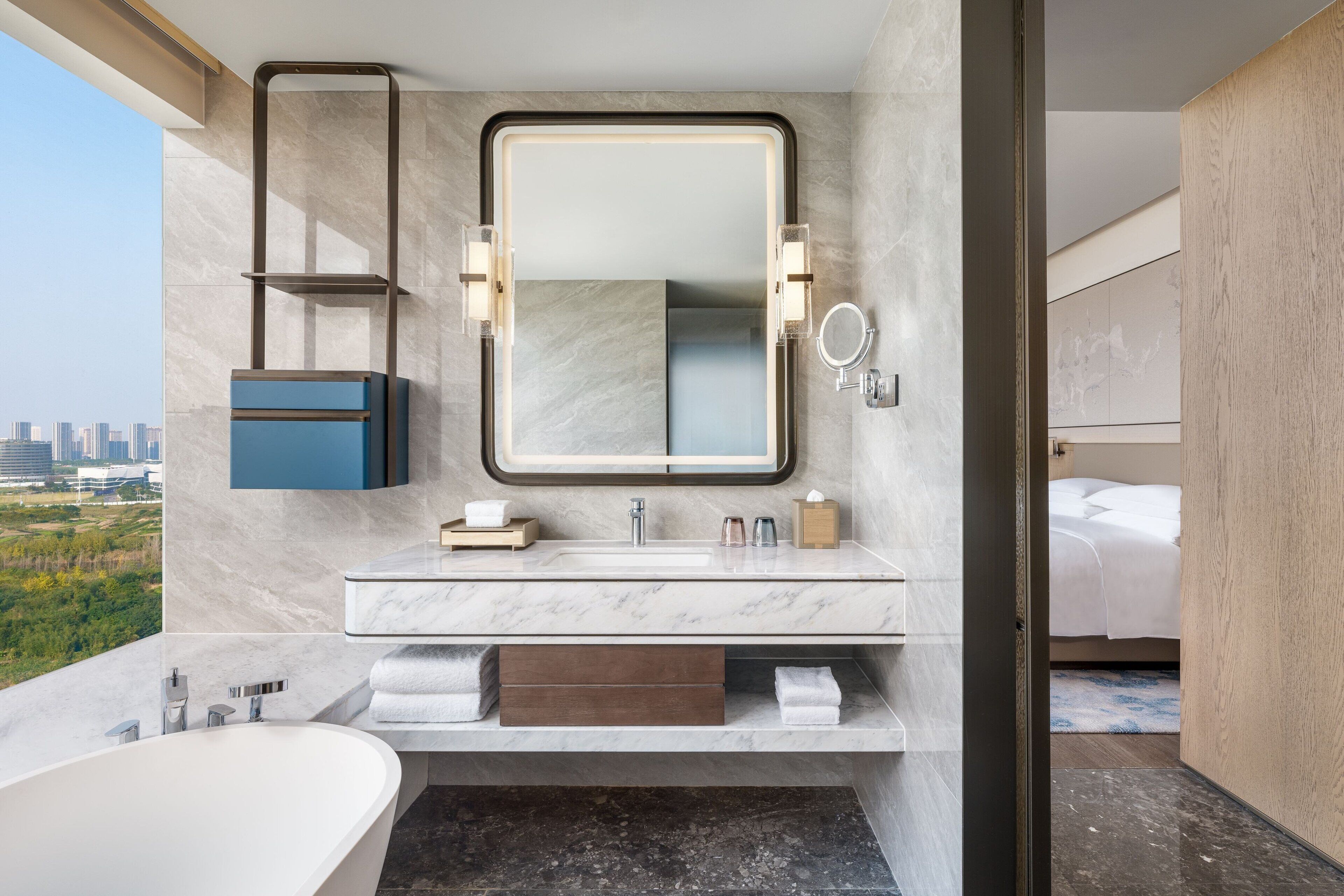 Ein modernes Badezimmer mit großem Spiegel, einer Badewanne und einem Waschtisch mit Marmorplatte.