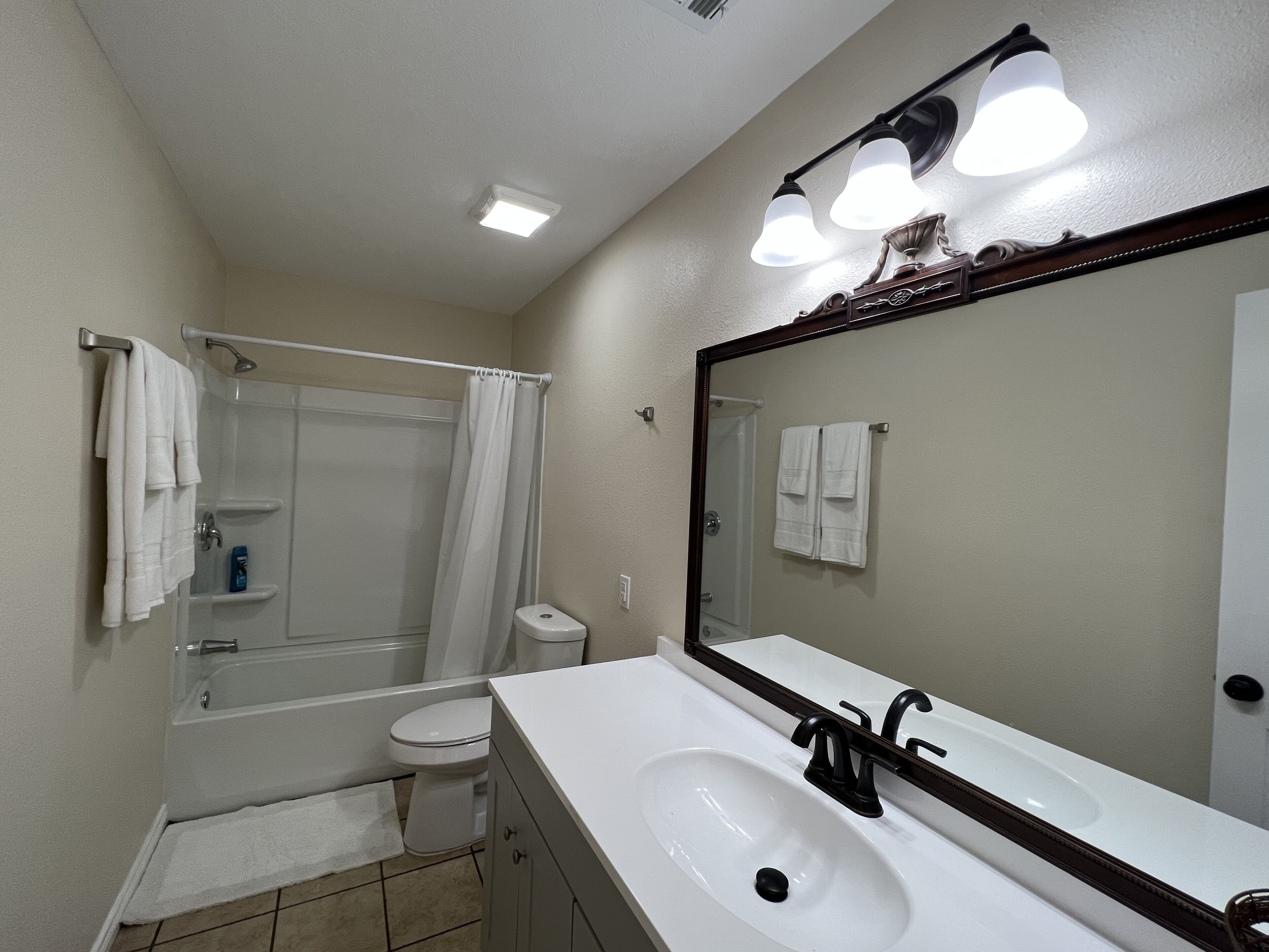 A bathroom with a white sink, a mirror, a shower, and a toilet.