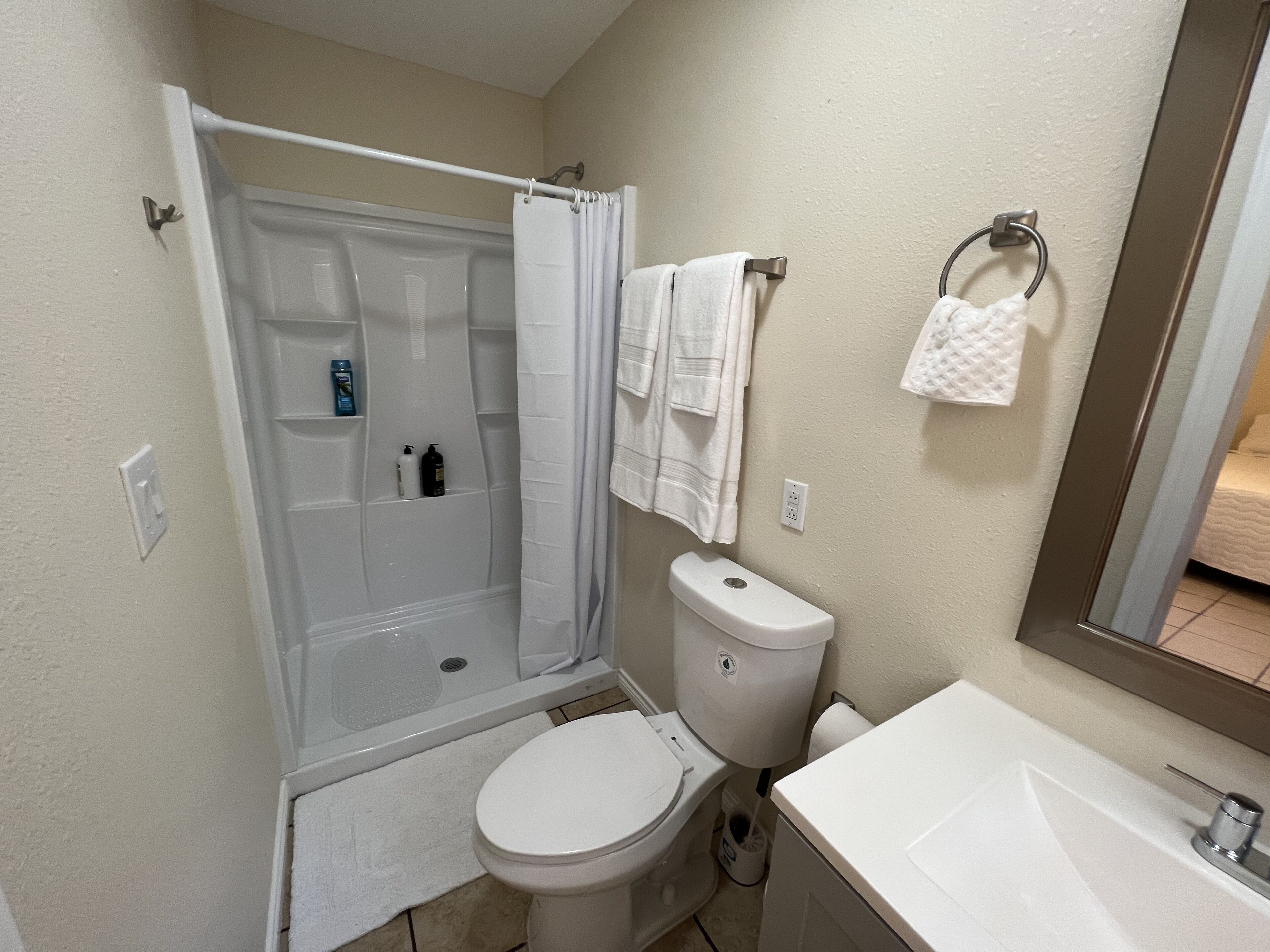 Une salle de bain avec douche, toilettes et lavabo.