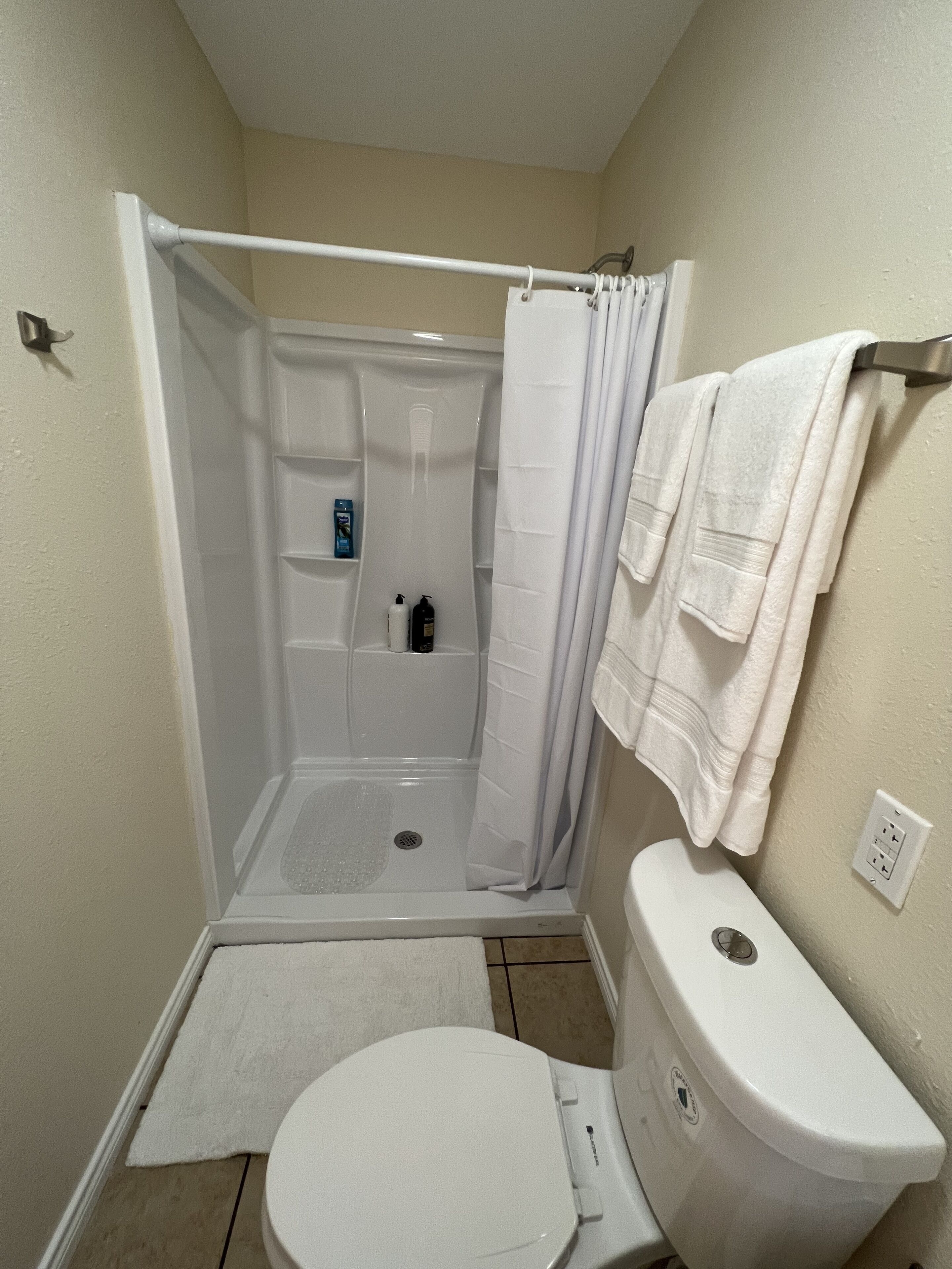 Ein kleines Badezimmer mit Dusche, Toilette und Handtuchhalter.