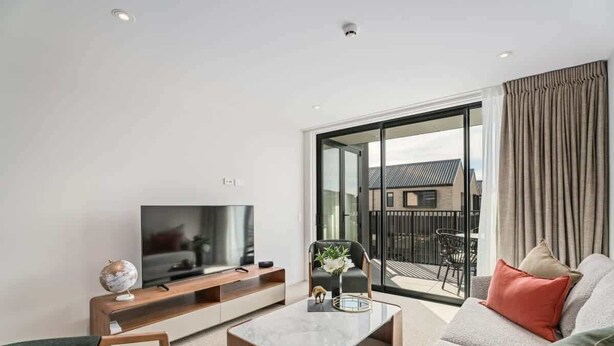 Een moderne woonkamer met een flatscreen televisie, een bijzettafeltje en een bank.