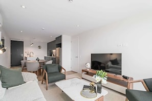 Un salon moderne comprenant un canapé, une table basse, un téléviseur et un coin repas avec des chaises et une table.