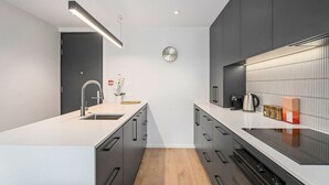 Een moderne keuken met een centraal eiland, een spoelbak en een klok aan de muur.