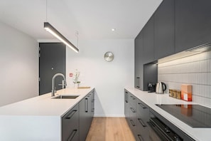 Una cocina moderna con una isla central, un fregadero y un reloj en la pared.