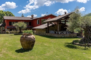 Una villa roja con un patio de piedra, mobiliario exterior y una maceta grande.