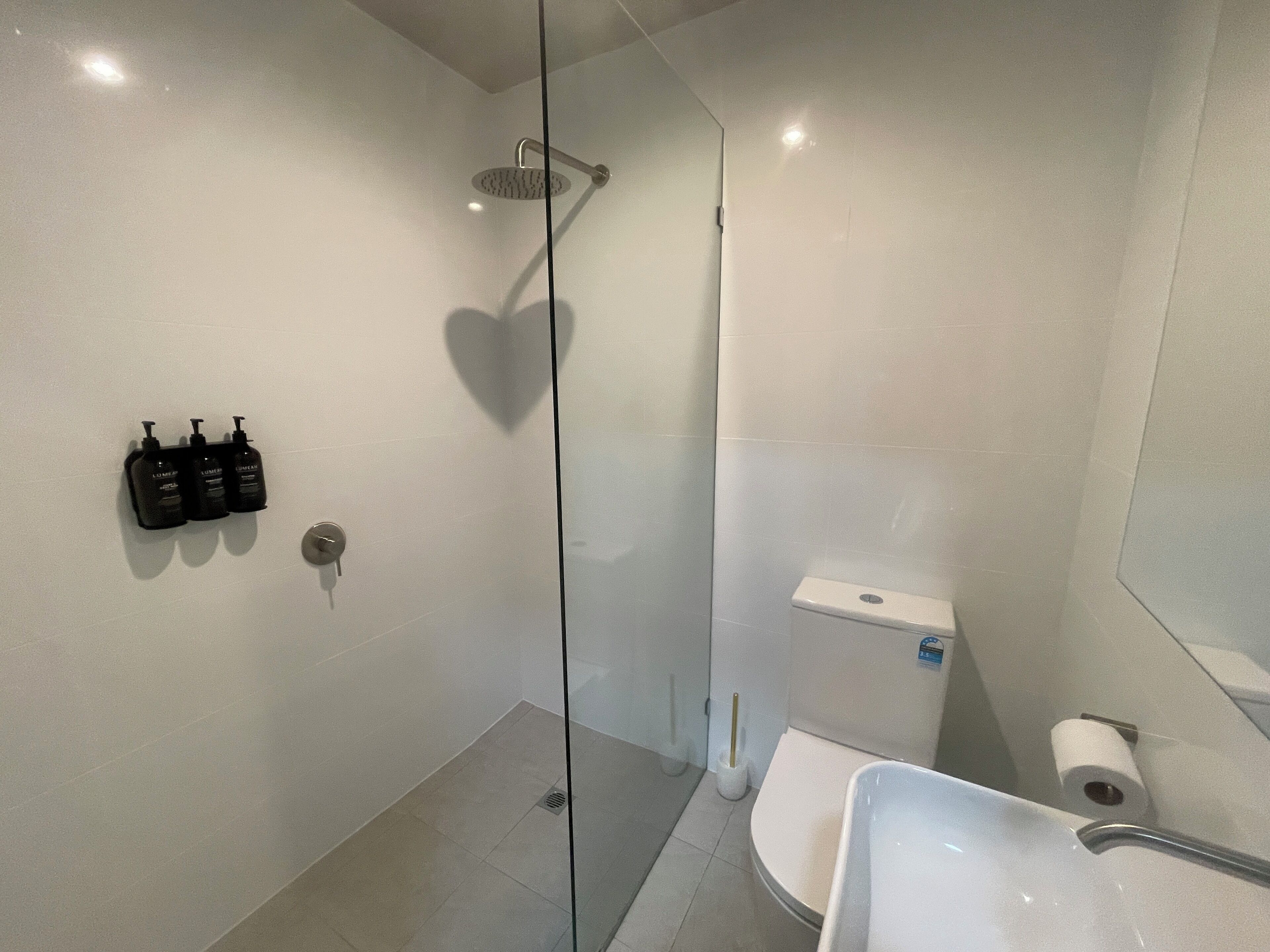 Un bagno moderno con doccia vetro-murata, un water e un lavandino.