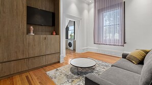 Ein modernes Wohnzimmer mit einem grauen Sofa, einem runden Couchtisch und einer Holzkabine.