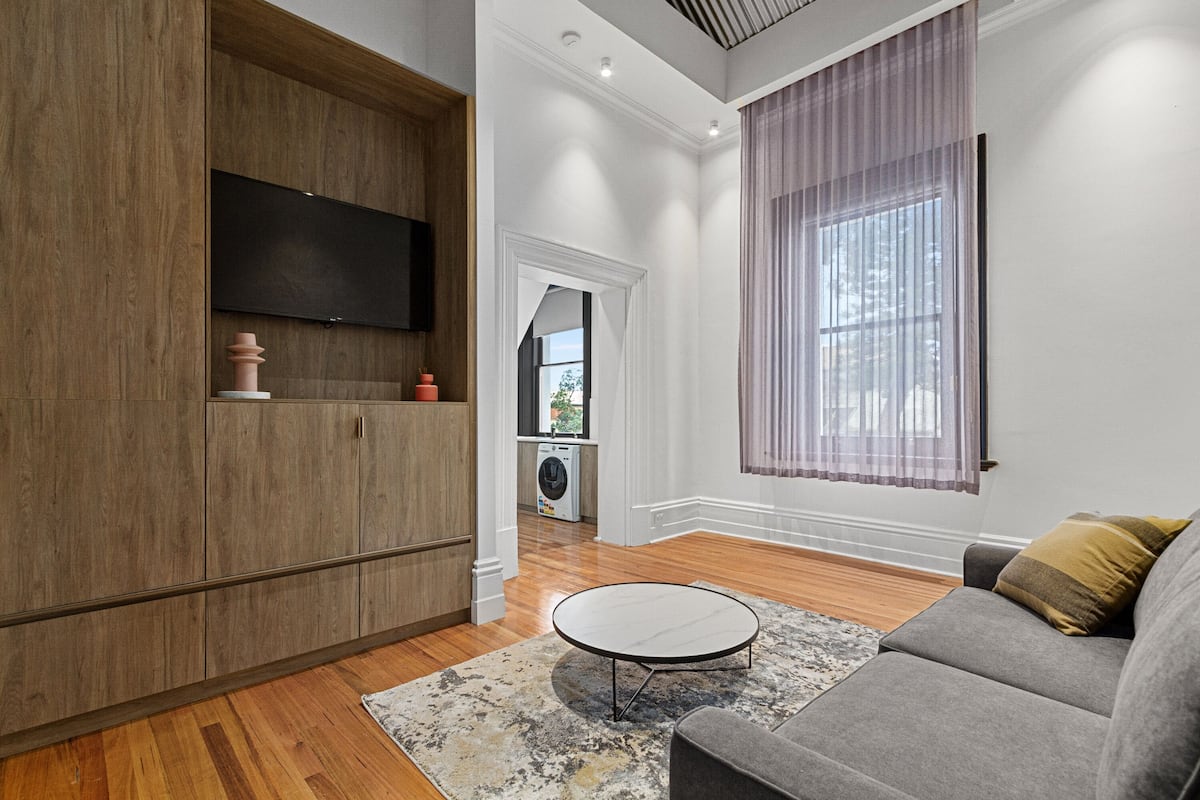 A modern living room with a grey sofa, a round coffee table, and a wooden cabinet.