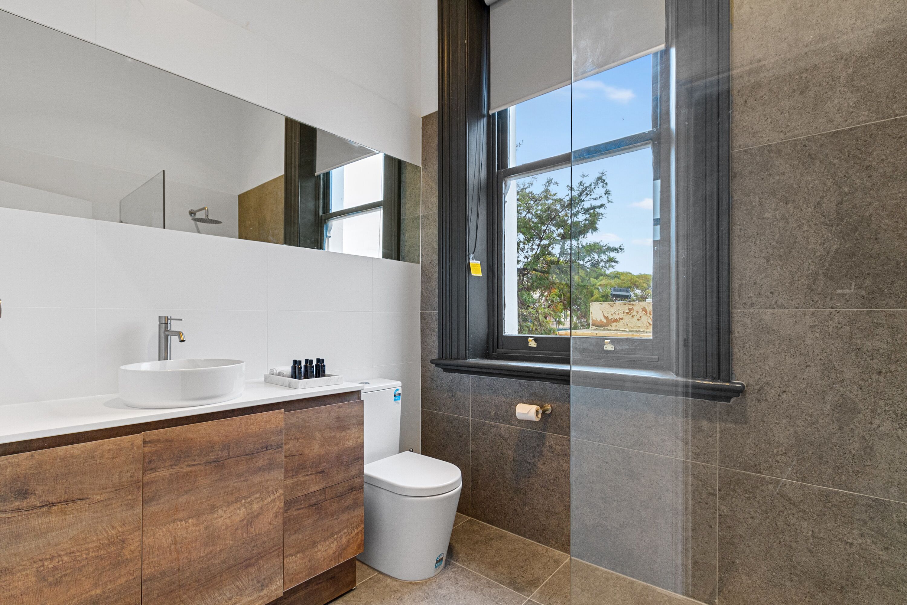 Ein modernes Badezimmer mit einem weißen Waschbecken, einer Toilette und einem großen Spiegel.