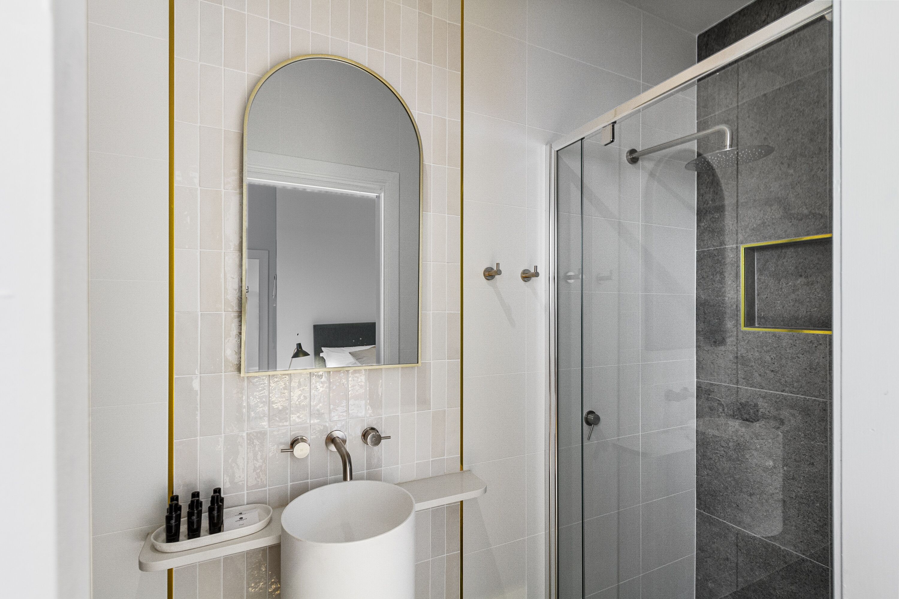Une salle de bain avec un lavabo blanc, un miroir et un espace douche.