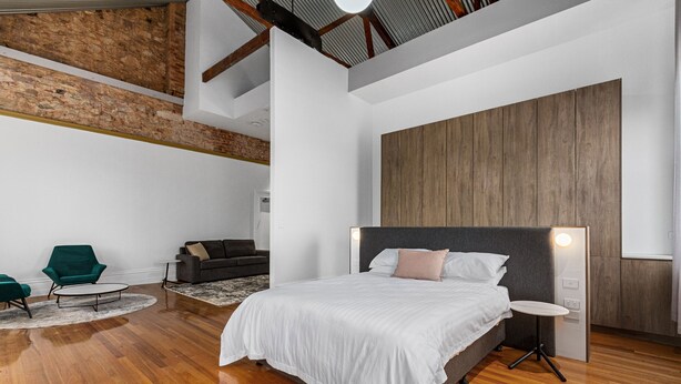 Ein modernes Schlafzimmer mit einem großen Bett, einem kleinen runden Tisch und einem grünen Sessel.