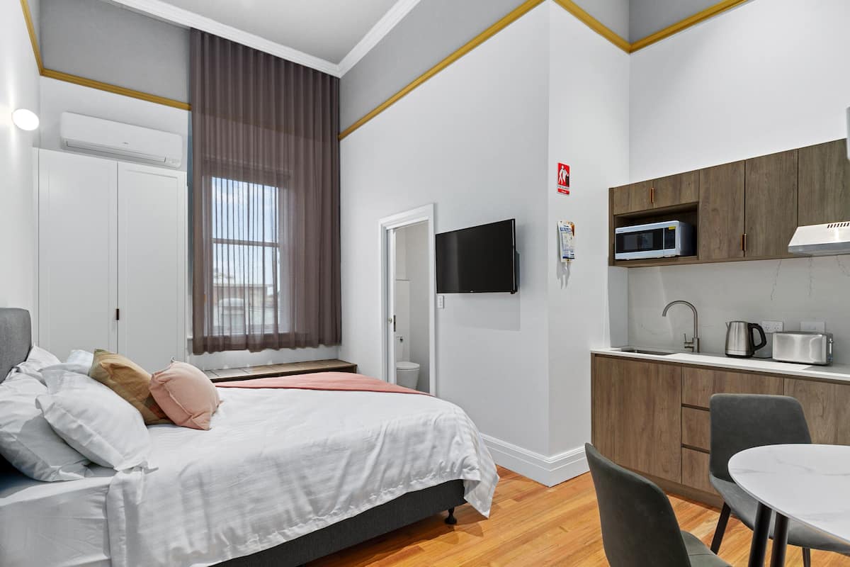 A modern hotel room with a bed, a desk, a microwave, and a TV.
