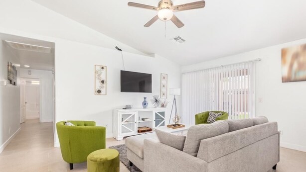 Uma sala de estar moderna com um sofá cinzento, uma poltrona verde e um console branco com uma televisão de tela plana.