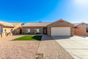 A single-story house with a garage, a front lawn, and a paved driveway. - 4BR Furnished Phoenix Home for Extended Stays (Phoenix)