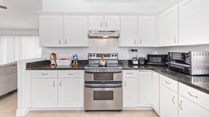 Uma cozinha moderna com armários brancos, eletrodomésticos de aço inoxidável e bancada de granito.