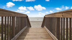 A wooden boardwalk leading to a beach with a clear sky. - Spectacular Ocean Views and Steps from the Beach (Oak Island)