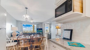 A modern kitchen with white cabinets, a granite countertop, and a microwave. - Spectacular Ocean Views and Steps from the Beach (Oak Island)