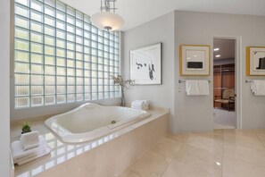 A modern bathroom with a freestanding bathtub, a large window with a view, and a walk-in closet.