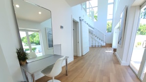 Un intérieur moderne avec un plancher en bois, un bureau blanc, une chaise et un grand miroir.