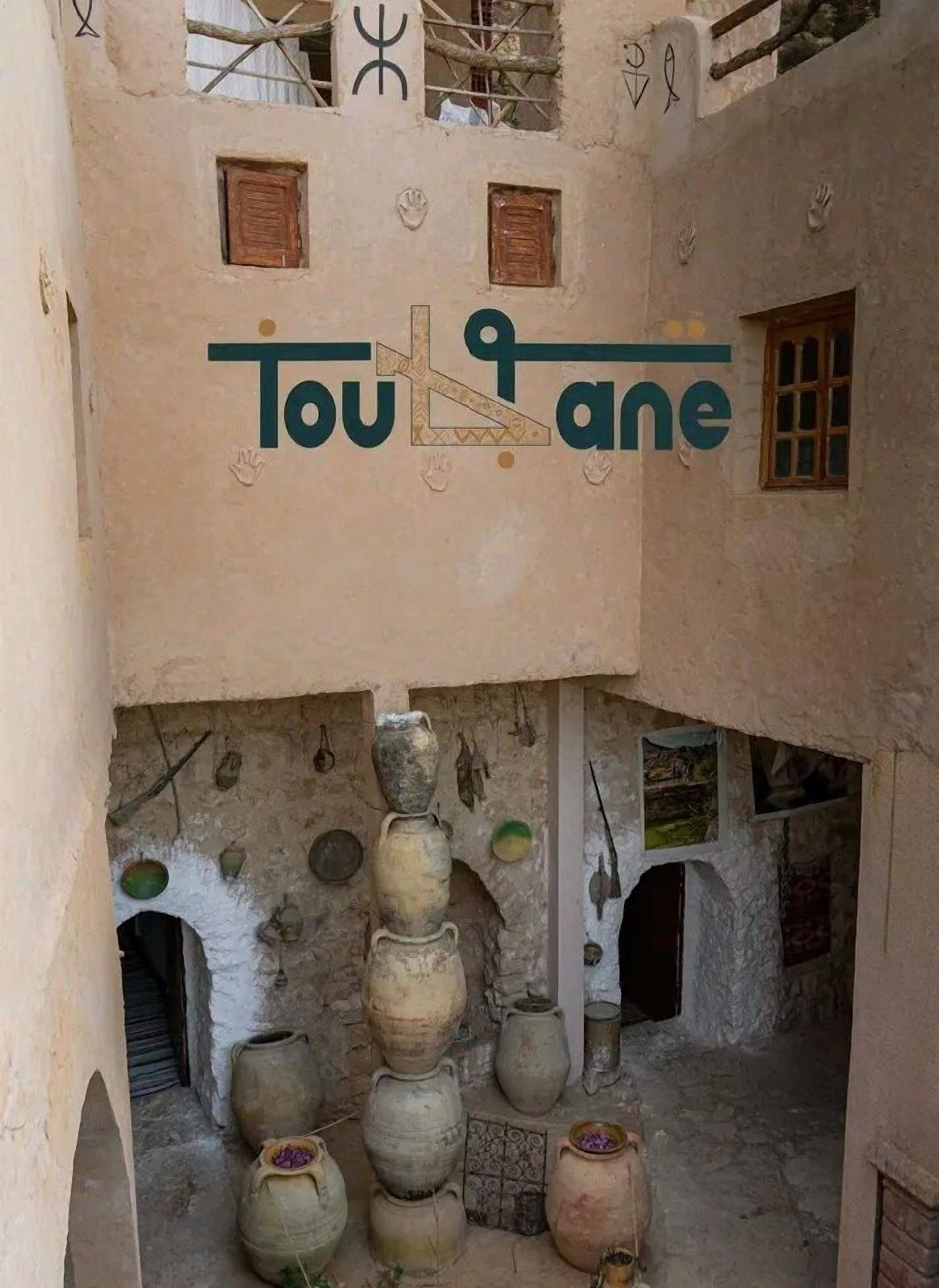 A courtyard with stacked pottery and a sign reading "Touane".