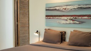 A bedroom with a bed, a painting, a lamp, and a wooden door. - The Saya House Villa by Betterplace (Kerobokan)
