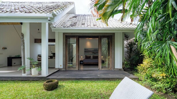 A modern house with a covered patio, a grassy lawn, and a seating area. - The Saya House Villa by Betterplace (Kerobokan)