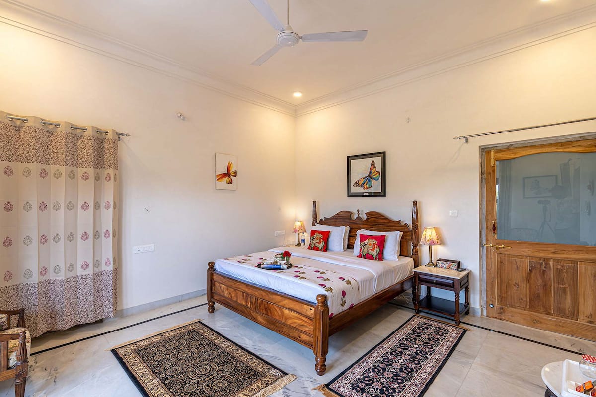 A bedroom with a wooden bed, two nightstands, a ceiling fan, and a large wooden door.