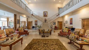 Amplia sala de estar con una imponente escalera, varios conjuntos de asientos y un gran tapete decorativo.