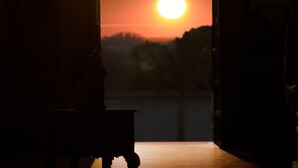 Vista interior de un edificio con un acceso a una escena de atardecer al aire libre.