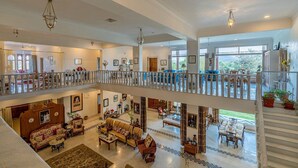 Un interior espacioso de varios niveles con una imponente escalera, techos altos y grandes ventanales con vistas al exterior.