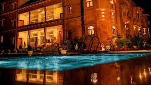 Un edificio de varios pisos con una piscina al frente.