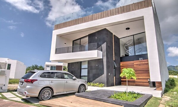 A modern two-story house with a car parked in front. - Villa 21: Private Rooftop Pool & BNayar Beach Club (Cruz de Huanacaxtle)