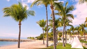 Een strand met palmbomen, een zandstrand en witte tenten.