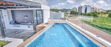 Une piscine sur le toit, dotée d’un design moderne, entourée d’une rambarde en verre et offrant une vue sur le paysage urbain.