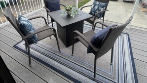 Eine Terrasse mit Tisch und Stühlen mit Blick auf einen See und Häuser.