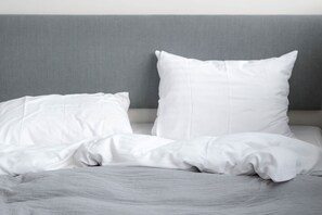 A bed with white bedding and a grey headboard. - South Studios by Daniel & Jacob's (København)