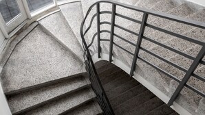 A spiral staircase with metal railings and a view of parked cars outside. - South Studios by Daniel & Jacob's (København)
