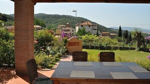 A covered outdoor seating area with a table and chairs, overlooking a village with houses and greenery. - Villa Raissa Grande: A characteristic and welcoming two-story villa immersed in a splendid landscape, in a lovely little hamlet, with Free WI-FI. (Montaione)