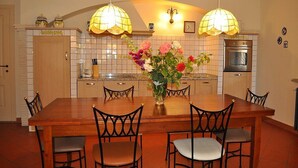 A kitchen with a wooden dining table, chairs, a vase with flowers, pendant lights, and a stove. - Villa Raissa Grande: A characteristic and welcoming two-story villa immersed in a splendid landscape, in a lovely little hamlet, with Free WI-FI. (Montaione)