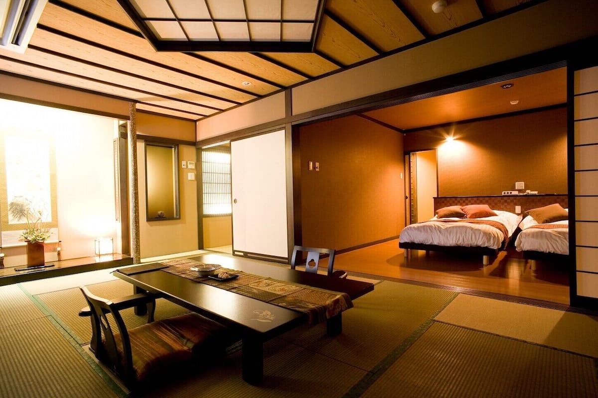 Une pièce de style japonais traditionnel, avec un sol recouvert de tatamis, une table basse et un lit équipé de futons.
