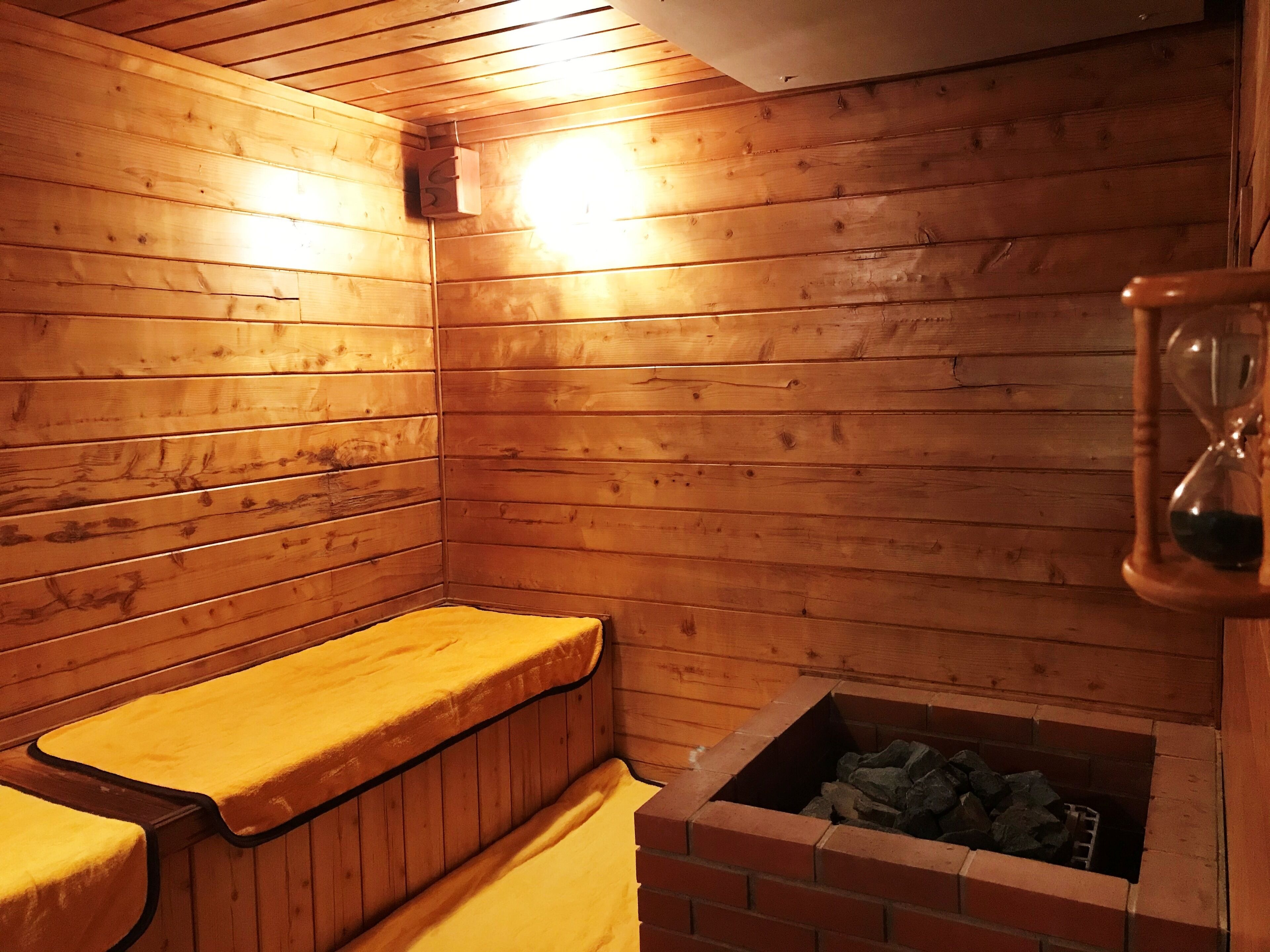 A sauna room with wooden walls, a bench, and a brick sauna floor.