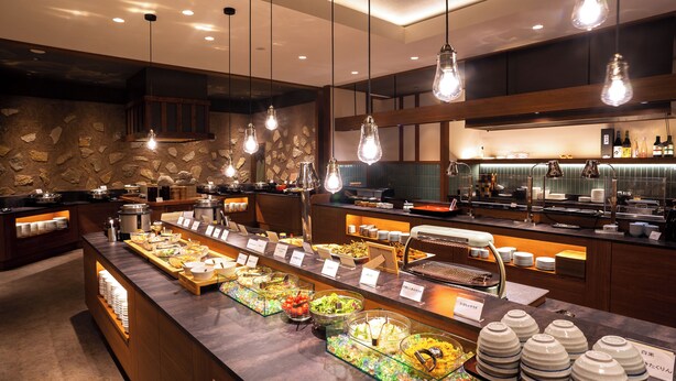 Een buffetgedeelte met diverse food stations, een koffiebar en een bar met flessen.