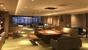 Een ruime hotellobby met een grote zithoek, een open haard en een uitzicht op de stad door grote ramen.