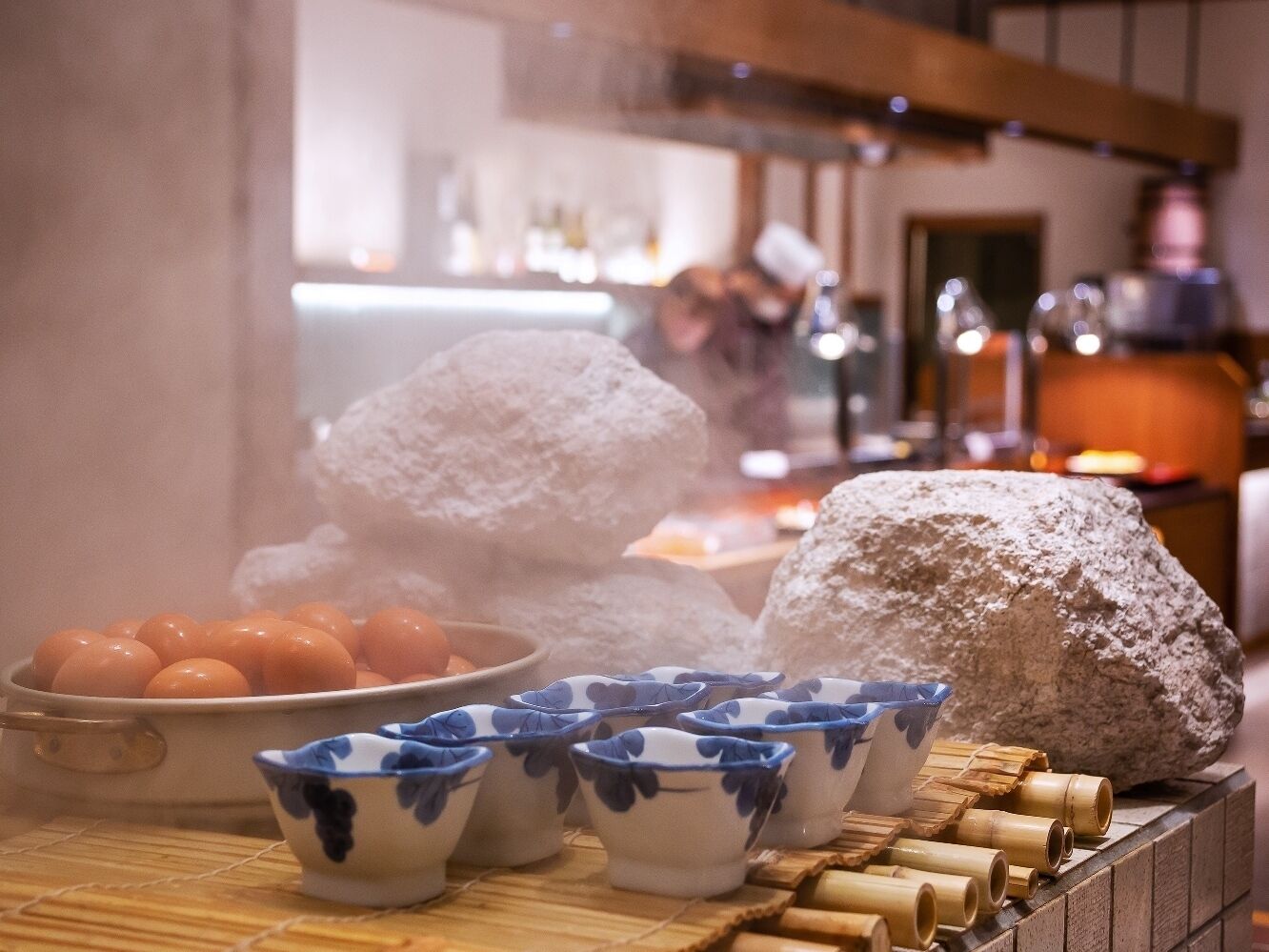 A traditional Japanese tea ceremony setup with a teapot, cups, and a large rock.