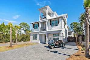 Uma casa de dois andares com entrada por automóvel e um carrinho de golfe estacionado na frente.